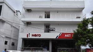 A multi-story building with a white facade, featuring a 'Hero' sign on the ground floor and an 'AKT' sign on the upper level. - Hotel Waanderers Howff (Port Blair)