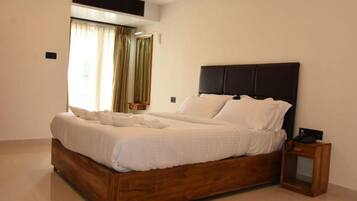 A modern bedroom with a wooden bed frame, white bedding, and a nightstand with a lamp.