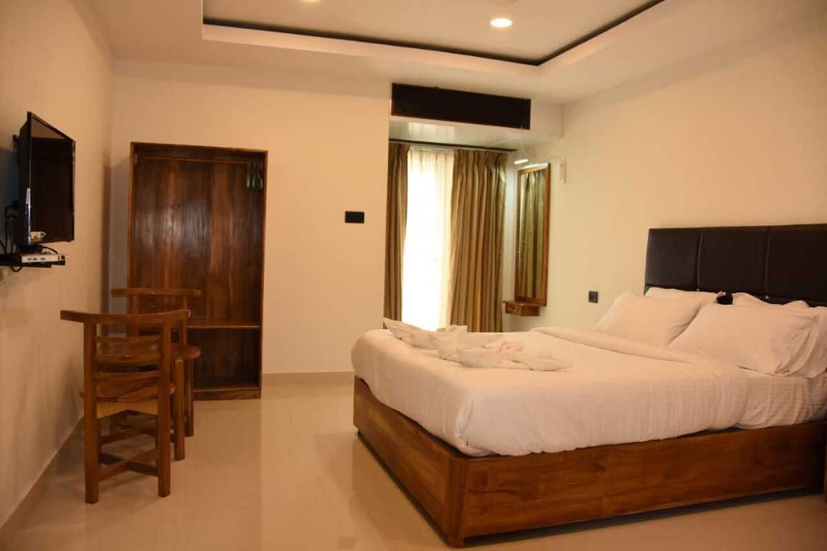Un dormitorio con una cama de madera, un escritorio y un televisor en la pared.