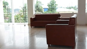 A spacious room with a large window offering a view of greenery and buildings outside. - Hotel Waanderers Howff (Port Blair)