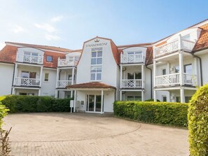 A hotel with a central entrance, multiple balconies, and a clear sky.