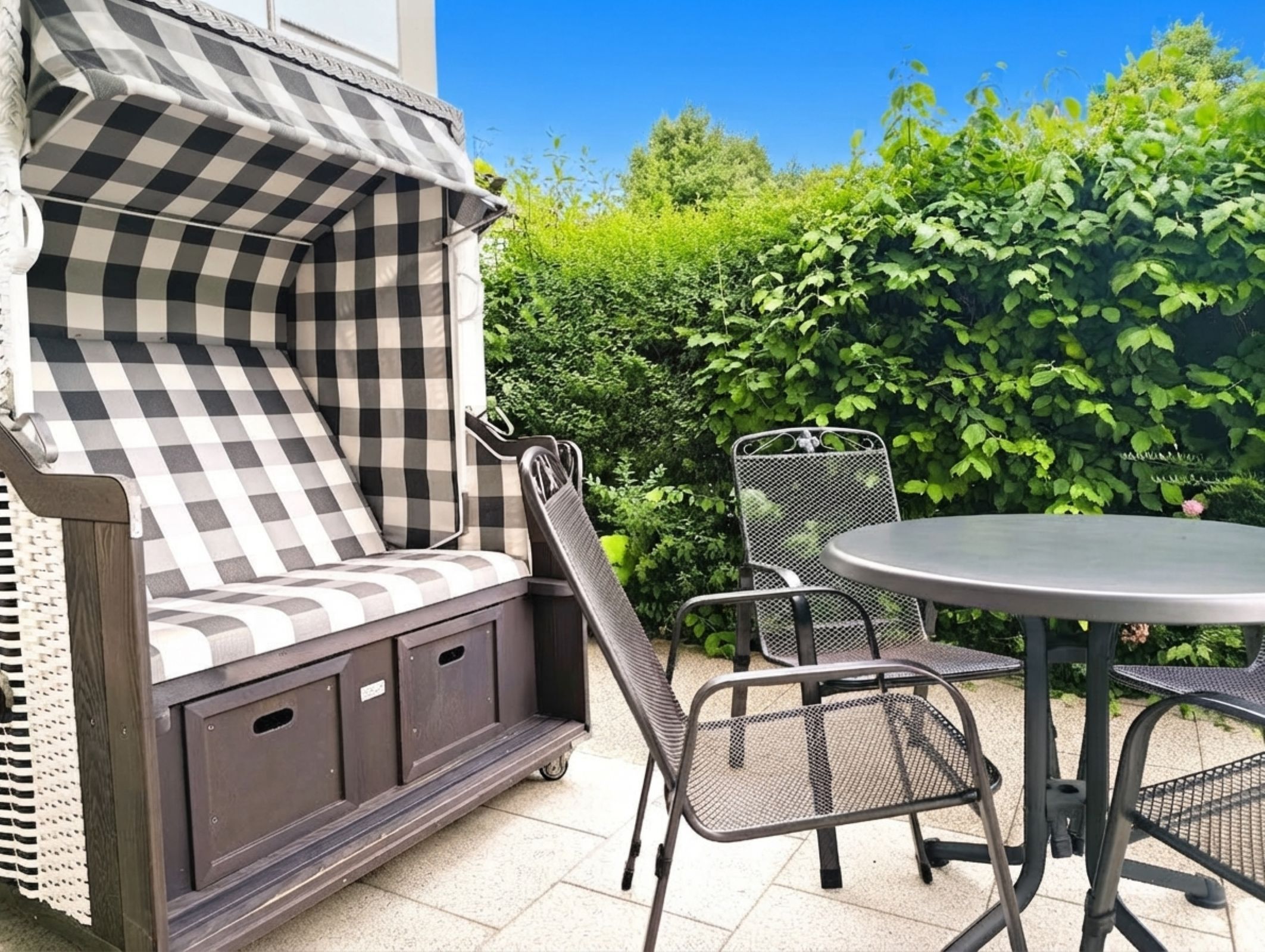 A patio area with a checkered outdoor seating arrangement, a round table, and chairs.