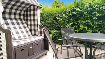 A patio area with a checkered outdoor seating arrangement, a round table, and chairs.