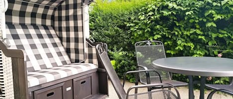 Un espacio de patio con una disposición de asientos al aire libre a cuadros, una mesa redonda y sillas.