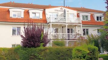 Ein zweistöckiges Gebäude mit einem Balkon und einem Schild, auf dem 'STRANDKINE' steht.