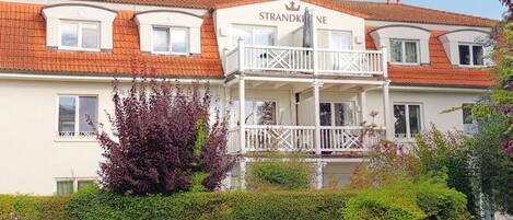 Ein zweistöckiges Gebäude mit einem Balkon und einem Schild, auf dem 'STRANDKINE' steht.