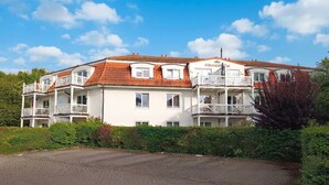 A multi-story hotel with a red-tiled roof, balconies, and a paved driveway. - Residence Strandkrone 02 - Strandkrone 02 (Kühlungsborn)