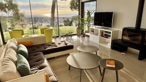 Una sala de estar moderna con un sofá, dos mesas redondas, un televisor y una chimenea.