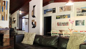 A cozy living room with a leather sofa, a fireplace, and a wall adorned with framed pictures. - Large family home Stellenbosch cbd (Stellenbosch Central)