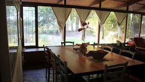 A dining area with a wooden table, chairs, and a view of a garden through large windows. - Large family home Stellenbosch cbd (Stellenbosch Central)