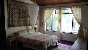 A bedroom with a bed, a hanging mosquito net, a window with curtains, and a wooden floor. - Large family home Stellenbosch cbd (Stellenbosch Central)