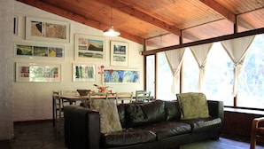 A living room with a black leather sofa, a dining table with chairs, and framed pictures on the wall. - Large family home Stellenbosch cbd (Stellenbosch Central)