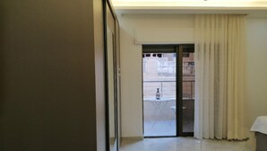 A room with a sliding door leading to a balcony with a view of buildings. - Amazing one Bedroom Apartment in Amman,elwebdah 1 (Amman)