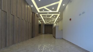 A hallway with wooden panel walls, a polished marble floor, and a ceiling with recessed lighting and geometric patterns. - Amazing one Bedroom Apartment in Amman,elwebdah 1 (Amman)