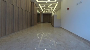 A hallway with wooden paneling on one side, a geometric ceiling design with recessed lighting, and a reception desk on the right. - Amazing one Bedroom Apartment in Amman,elwebdah 6 (Amman)