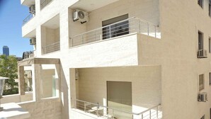 A multi-story building with balconies, air conditioning units, and a view of the cityscape. - Amazing one Bedroom Apartment in Amman,elwebdah 6 (Amman)