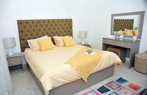 A neatly arranged bedroom with a large bed, bedside tables, a dresser, and a mirror. - Amazing one Bedroom Apartment in Amman,elwebdah 6 (Amman)