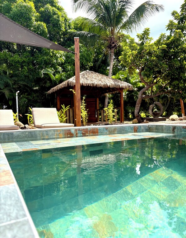 A clear swimming pool with lounge chairs and a thatched-roof structure. - Domaine Saint-François (Saint-François)