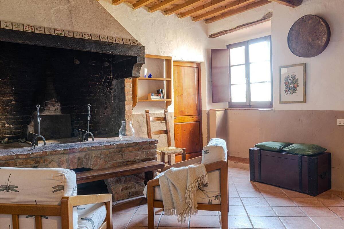 A rustic room with a stone fireplace, wooden furniture, and a window with blinds.