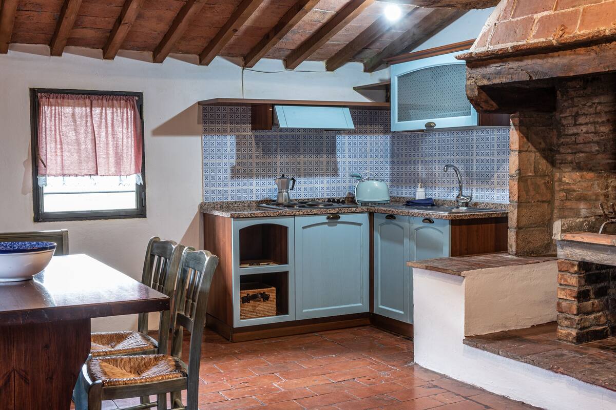 A kitchen with wooden cabinets, a tiled backsplash, and a brick fireplace.