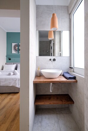 A modern bathroom with a large white sink, wooden countertop, and a hanging pendant light. - The Flirty Athens (Kallithea)