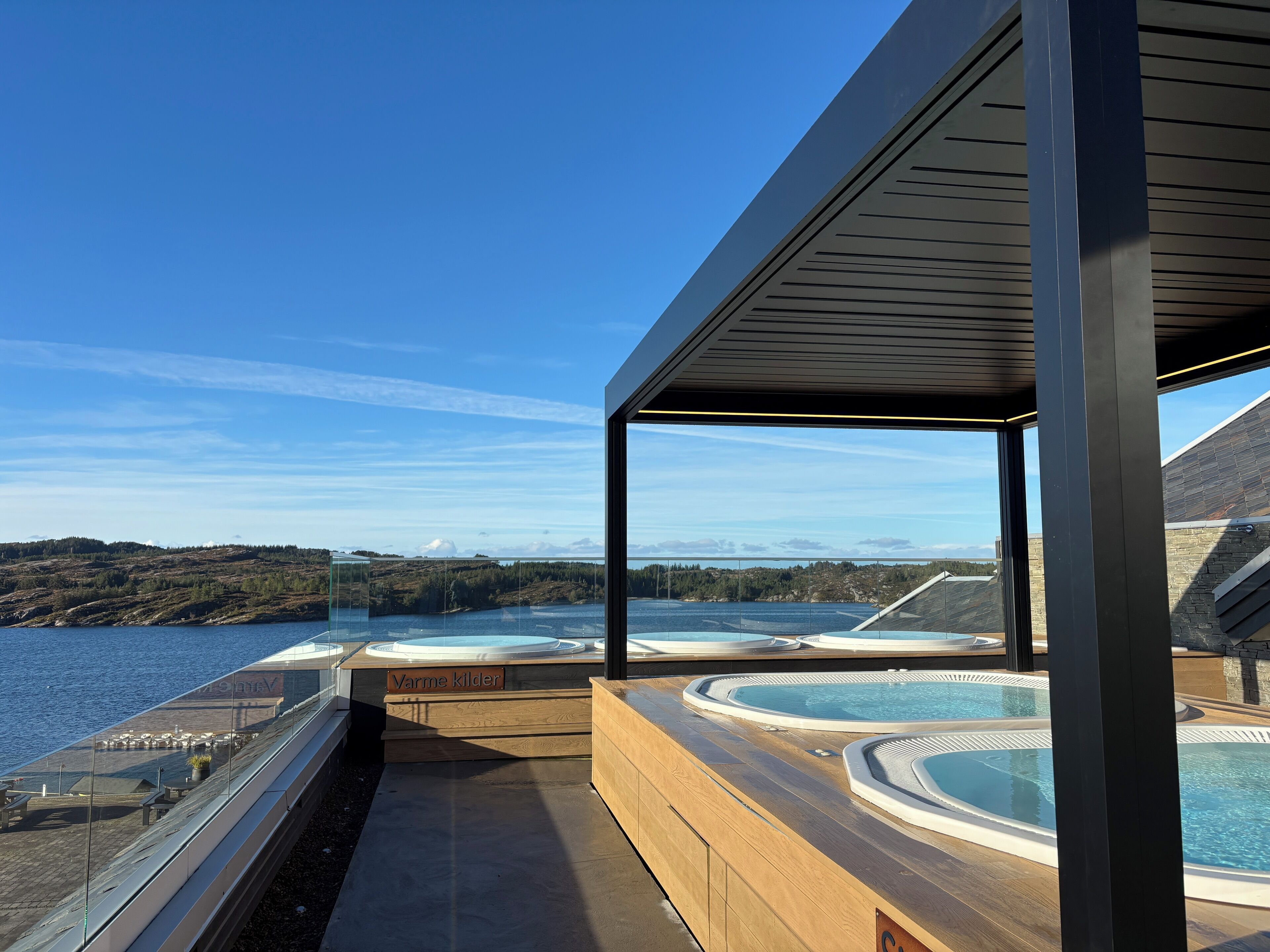 A modern outdoor hot tub area with clear views of a lake and distant hills.