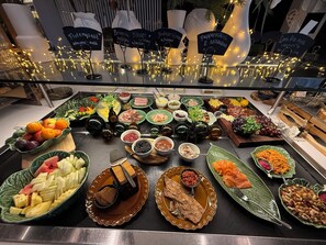 A buffet table with various food items and decorative lights.