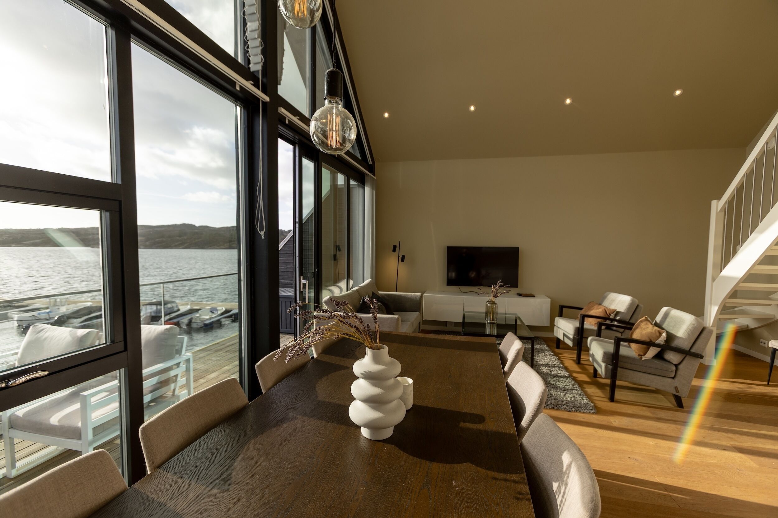A modern interior with a dining area, sofas, and a view of the water.