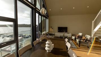 A modern interior with a dining area, sofas, and a view of the water.