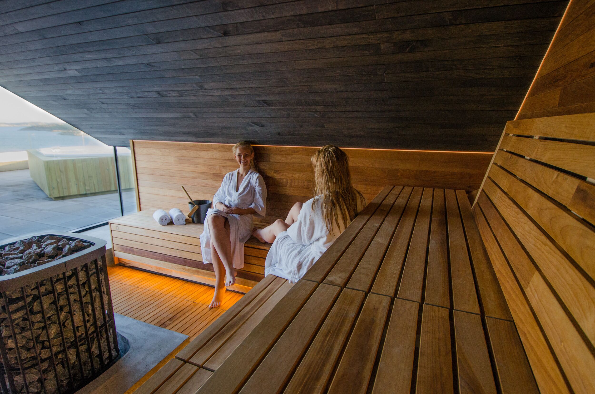 A wooden sauna with benches and a fire pit.