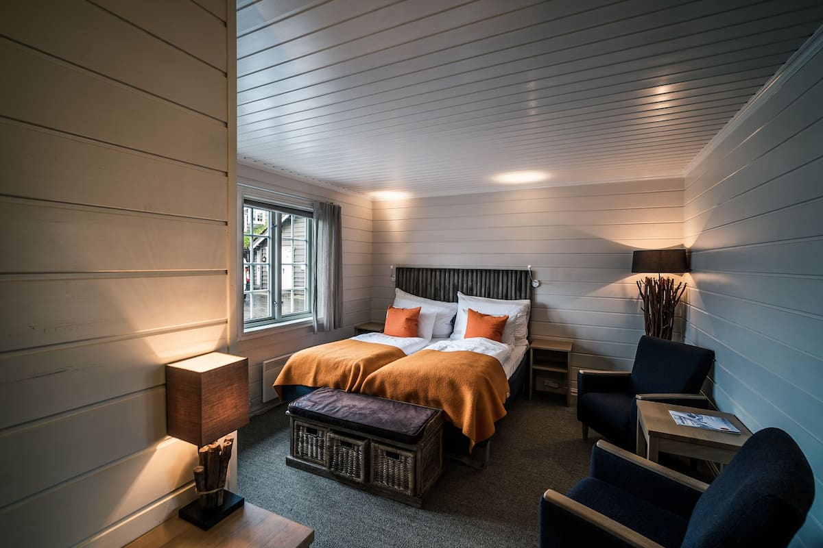 A bedroom with a bed, two bedside tables, a chair, a lamp, and a window.