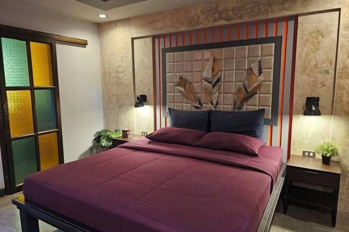 Une chambre à coucher comprenant un lit, des tables de chevet et une tête de lit agrémentée d’éléments décoratifs.