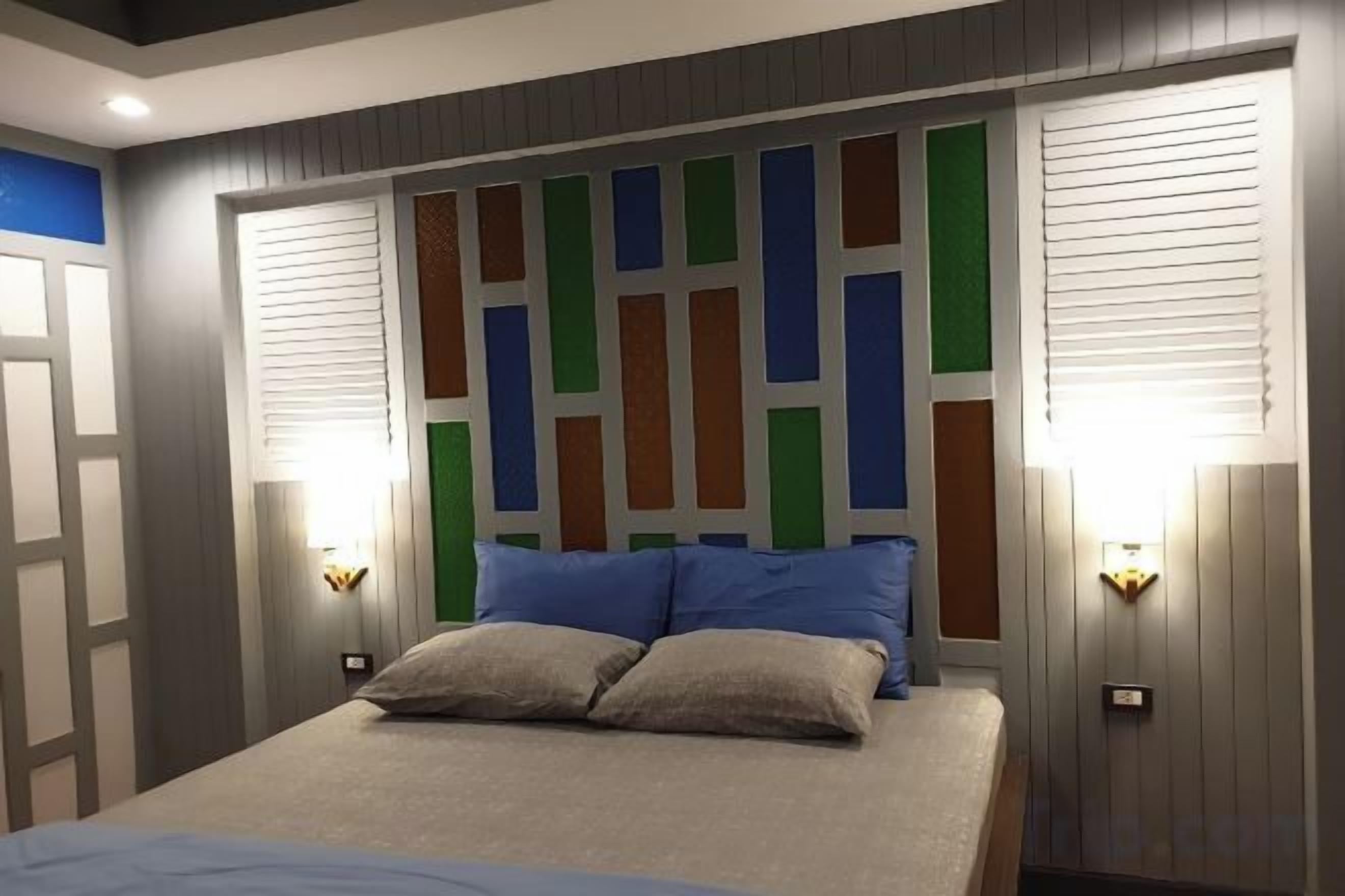 A bedroom with a bed, two bedside lamps, and a headboard with a geometric pattern.