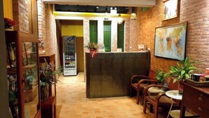 A reception area with a counter, chairs, a refrigerator, and a map on the wall. - Baan Baimai Boutique Room (Ayutthaya)