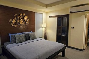A bedroom with a bed, a wall-mounted artwork, a nightstand, and a door with a sliding mechanism.
