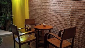 A brick wall, wooden chairs, and a round table in an outdoor setting. - Baan Baimai Boutique Room (Ayutthaya)