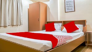 A neatly made bed with a red and white bedspread, a wooden headboard, and a nightstand with a lamp. - OYO 592 La Briana Guest House (Santa Fe)