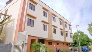 A multi-story building with a beige facade, multiple windows, and a gated entrance. - OYO 592 La Briana Guest House (Santa Fe)