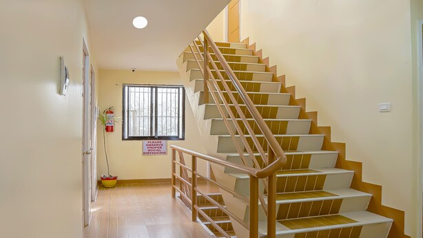 A staircase with wooden steps and metal railings, leading to an upper floor. - OYO 592 La Briana Guest House (Santa Fe)