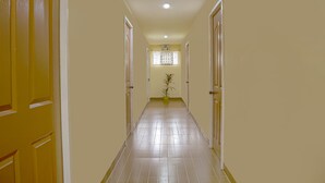 A hallway with yellow doors, a potted plant, and a window with lace curtains. - OYO 592 La Briana Guest House (Santa Fe)