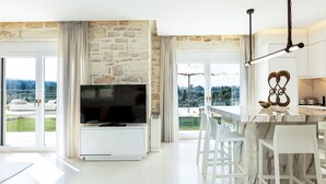 Eine moderne Küche mit Steinwand, einem Flachbildfernseher und einem Essbereich mit weißen Stühlen.