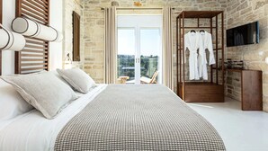 Ein Schlafzimmer mit einem großen Bett, einem Holzschrank, einem Fernseher und einem Balkon mit Blick.