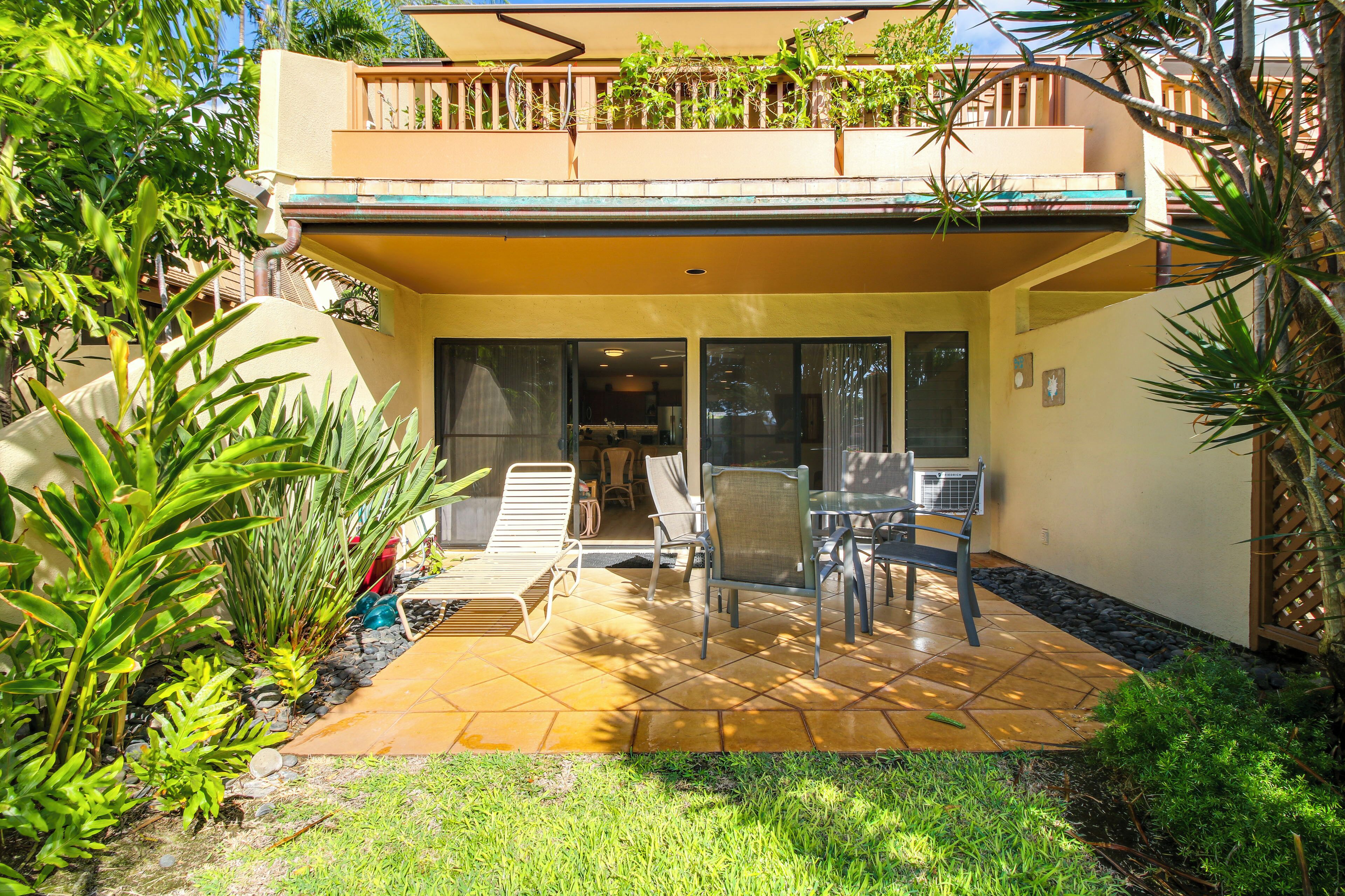 A two-story building with a patio area featuring outdoor furniture and a small garden.