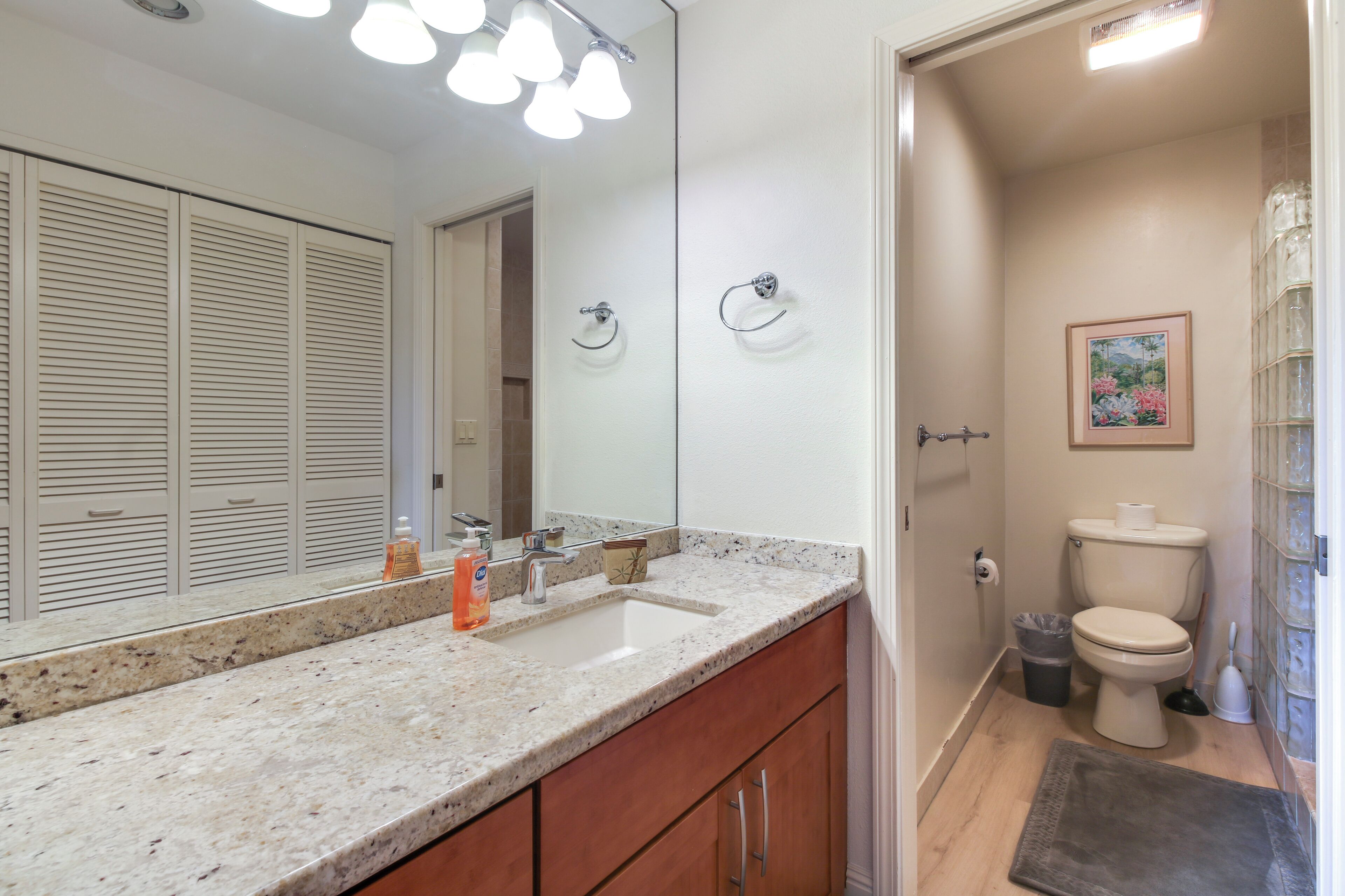 Une salle de bain équipée d’un lavabo, d’un miroir, de toilettes et de meubles de rangement.