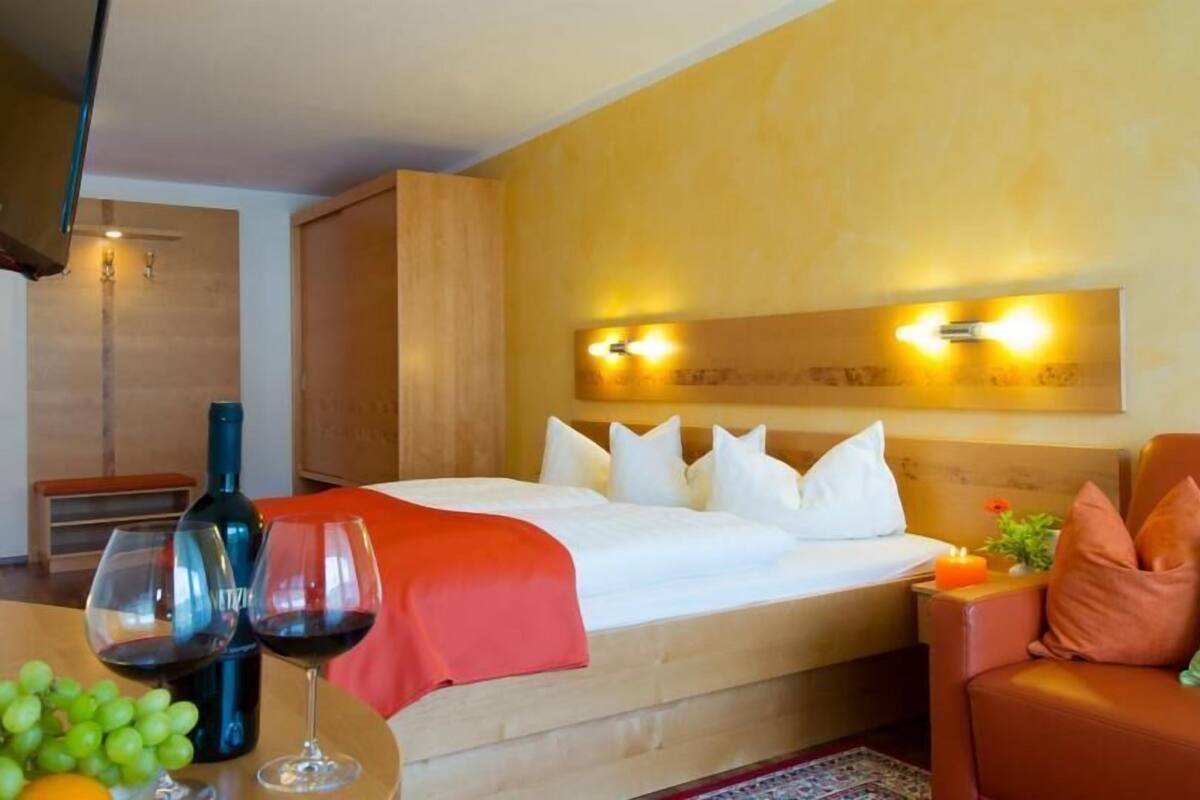 A hotel room with a bed, a seating area with a table, and a wall-mounted light fixture.