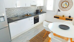 A modern kitchen with white cabinets, a black countertop, and a white dining table with orange legs. - Sea view apartment and private parking at 50 m. from the beach Salatar, Roses (Roses)