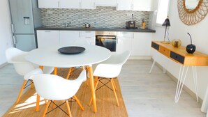 A modern kitchen with white cabinets, a grey refrigerator, and a round dining table with white chairs. - Sea view apartment and private parking at 50 m. from the beach Salatar, Roses (Roses)