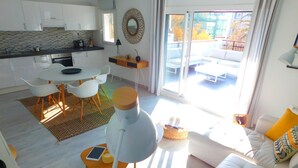 A modern living room with a white sofa, a dining area with white chairs, and a kitchen with white cabinets. - Sea view apartment and private parking at 50 m. from the beach Salatar, Roses (Roses)
