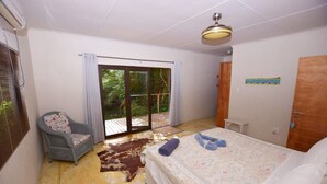A bedroom with a bed, a chair, a sliding glass door to a balcony, and a ceiling fan. - Baleia Azul 26 (Zitundo)