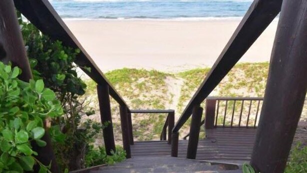 A wooden staircase leading to a beach with a pair of flip-flops on the steps. - Baleia Azul 26 (Zitundo)